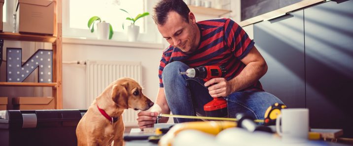 Man with power drill tape measure with dog