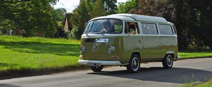 Classic Volkswagen Camper Van driving through a village